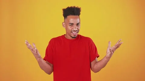 Young black man feeling aversion and shock, raising hands and refusing, orange Stock Footage 137977448