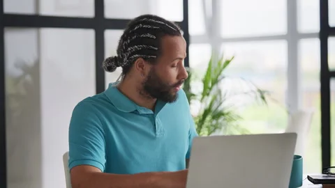 Young Black man freelancer typing on a laptop and drinking tea, remote work Stock Footage 333779658