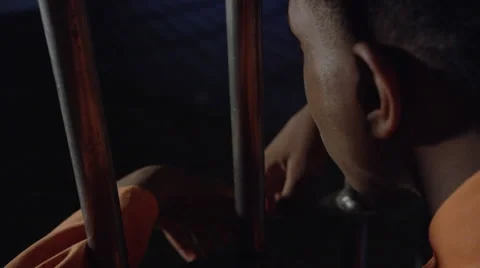 Young black man looking out from his prison cell Stock Footage 62706680