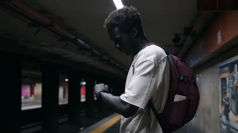 Young black man looks at the time impatiently while waiting for the subway Stock Footage 240325752