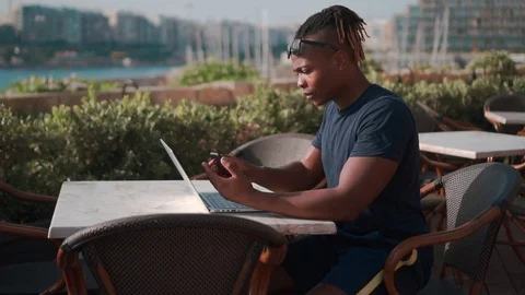 Young Black Man Multi Tasking Outside With Mobile Phone And Laptop Stock Footage 112800089