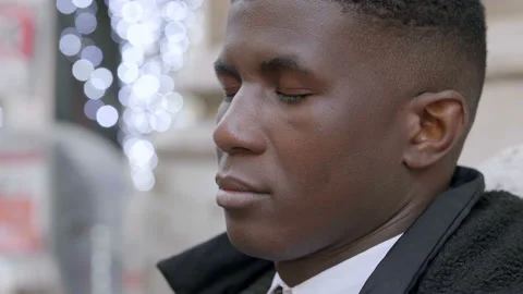Young black man opens his closed eyes and looking around - outdoors Stock Footage 132513607