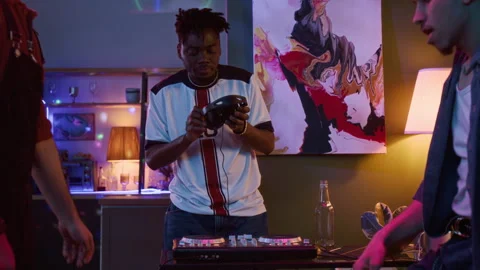 Young Black Man Playing on DJ Controller while Friends Dancing at Home Party Stock Footage 332064202