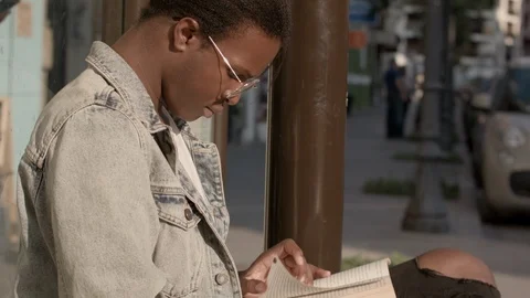 Young black man reading in the bus stop. Stock-Footage 92113079