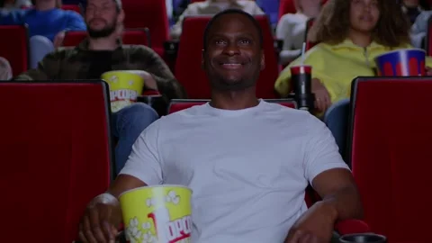 A young black man sits spellbound and watches a movie in a cinema, the premiere Stock Footage 267351066