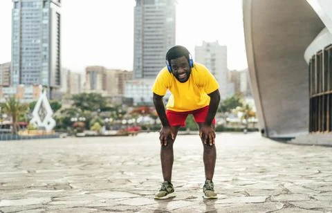 Young black man taking a rest after fast running workout while listening musi Stock Photos