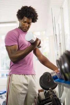Young black man taking weights from rack in gym Stock Photos
