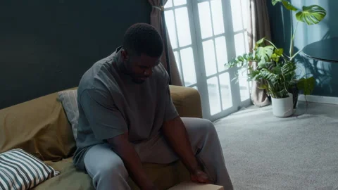 Young Black Man Under House Arrest Reminiscing Past Looking at Photo Album Stock Footage 313933061