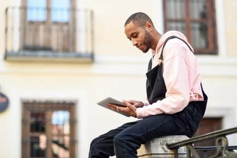 Young black man using digital tablet in urban background. Stock Photos