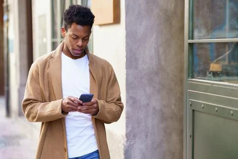 Young black man using his smartphone outdoors. Stock Photos