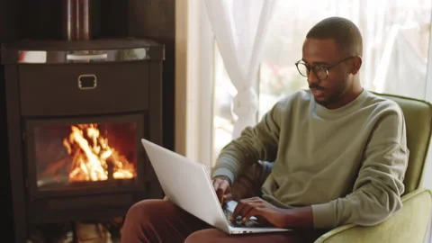 Young Black Man Using Laptop by Fireplace in Country House Vidéo 144660537