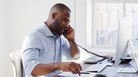 Young black man using phone and computer in office, close up Stock Footage 78937412