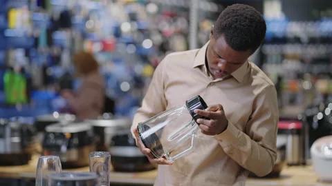 Young black man is viewing blender in home appliances store, choosing equipment Stock Footage 153136023