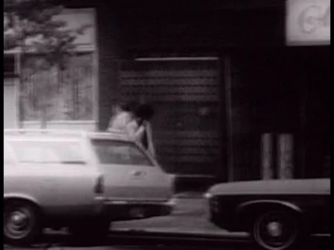 A young black man wanders the inner city and attempts to steal from a car to Stock Footage 75306554