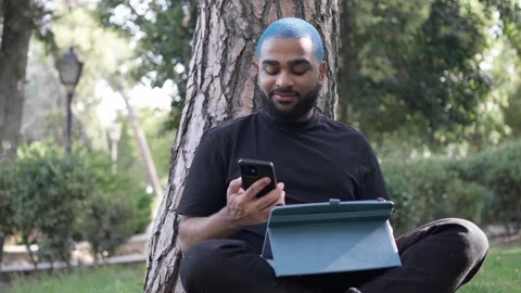 Young black man working remotely in a park with a tablet Stock Footage 287491421