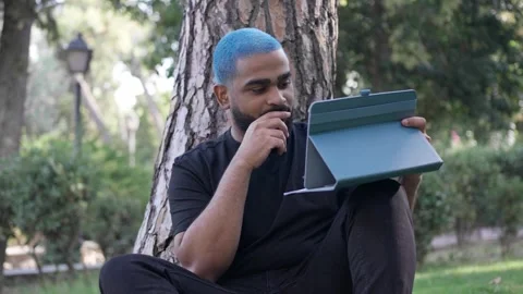 Young black man working remotely in a park with a tablet, Stock Footage 287491661