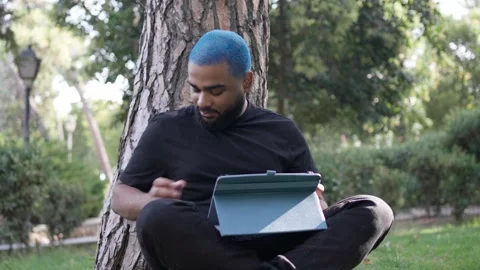 Young black man working remotely in a park with a tablet 스톡 동영상 287491680