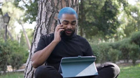 Young black man working remotely in a park with Stock Footage 287491707