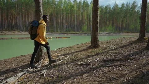 A young black man in a yellow cursor climbs up with a backpack uphill in the Stock Footage 154829326