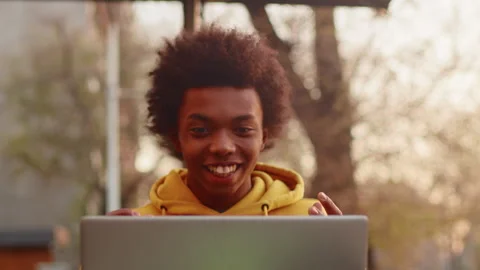 Young black programmer in casual clothes sitting outdoors with a laptop and Stock Footage 277190592