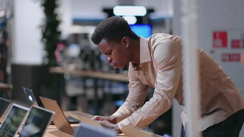 Young black programmer is choosing new laptop for work in electronics shop Stock Footage 153072676