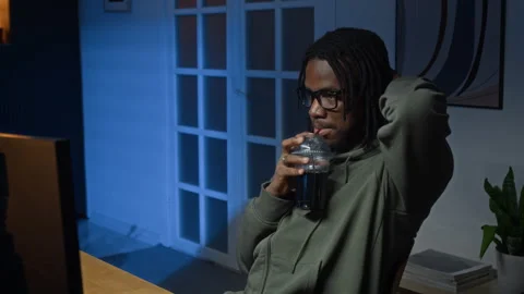 Young Black Programmer Drinking Soda while Reviewing Computer Code at Night 스톡 동영상 328243376