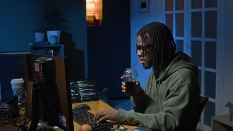 Young Black Programmer Drinking Soda while Hacking System at Night Home Office Stock Footage 328245790