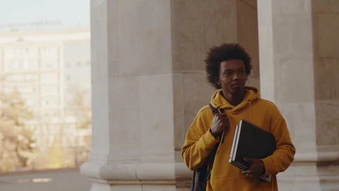 Young black programmer walking alongside the building outdoors after a Stock Footage 262441926
