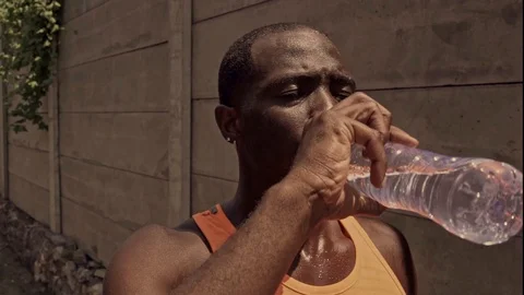 Young black runner man drinking water tired after running Stock Footage 128812951