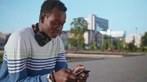 A young black student in stylish clothes sits and talks on a smartphone in the Stock Footage 155337008