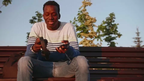 A young black student in stylish clothes sits and talks on a smartphone in the Stock Footage 155643320