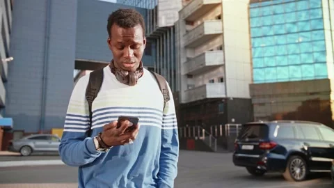 A young black student in stylish clothes sits and talks on a smartphone in the Stock Footage 155643552