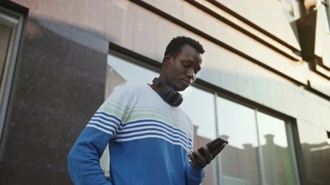 A young black student in stylish clothes sits and talks on a smartphone in the Stock Footage 155691687