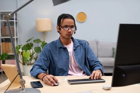 Young black student using computer at home and writing code online Stock Photos