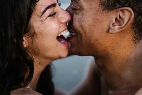 Young black tourist kissing happy beloved against sea Stock Photos