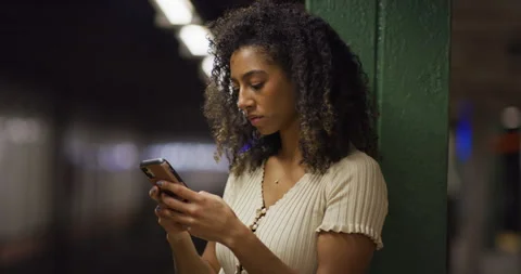 Young black woman using smartphone cell phone at subway platform 8k 動画素材 254729369