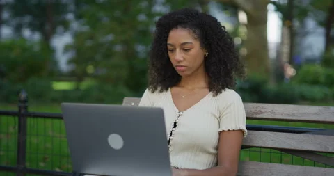 Young black woman using working on laptop computer in a park 8k Vídeos de archivo 254437500