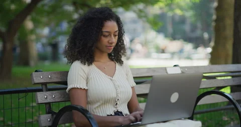 Young black woman using working on laptop computer in a park 8k Vídeos de archivo 254445447