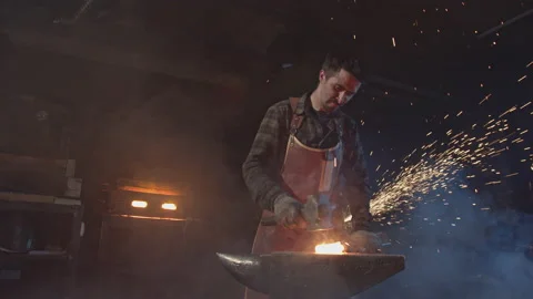A young blacksmith forges red-hot metal with force Видео 146581038