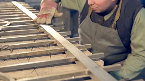 A young blacksmith hand in gloves touches metal products 스톡 동영상 77025941