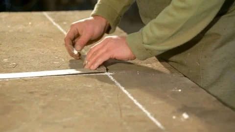 A young blacksmith uses gon to draw a line on the table Stockbeeldmateriaal 76363129