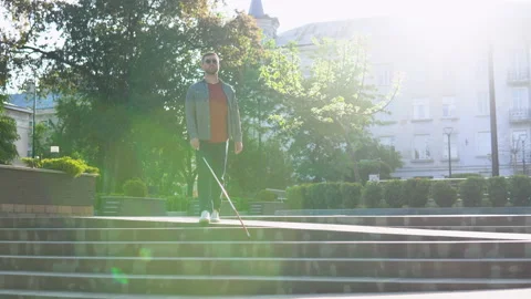 Young blind man with with a cane alone outdoors. Male person wearing glasses and Stock Footage 194850252
