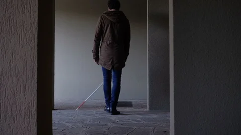 Young blind man orientating himself with his walking cane- back view Stock Footage 119970424
