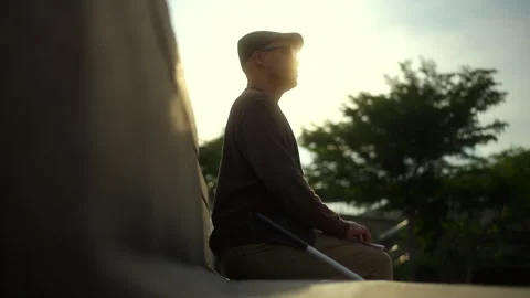 The young blind man reading braille while sitting on the bench in the city park  Stock Footage 276486032