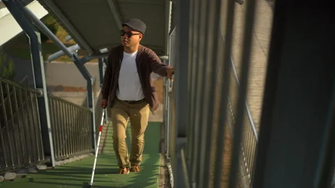 The young blind man walking down the stairs using a white cane, a disabled man. Video stock 276485291