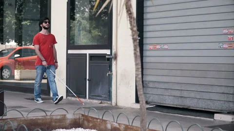Young blind man walking on the sidewalk with the help of his stick Stock Footage 131973974