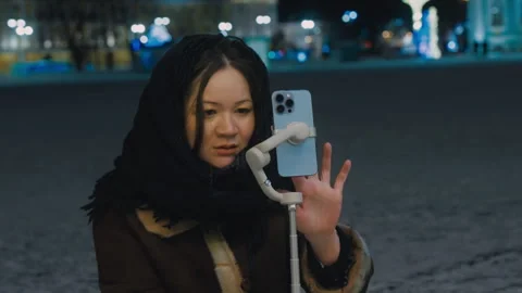 A young blogger sets up a photo timer on her mobile phone. A cute Asian girl Stock Footage 265568030