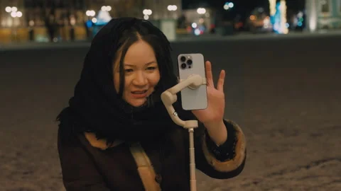 A young blogger sets up a photo timer on her mobile phone. A cute Asian girl Stock Footage 267900448