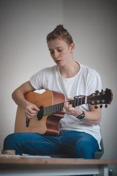 Young blond boy is trying to learn a new skill and that is playing a musical  Stock Photos
