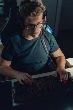 Young blond guy playing video games, playing on his laptop in the dark Stock Photos